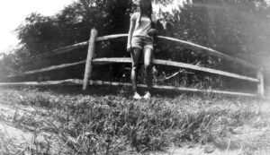 A woman standing in front of a wooden fence.