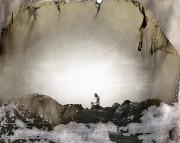 A person standing in the snow near some rocks.