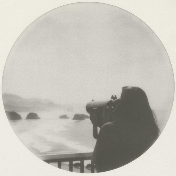 A woman is taking pictures of the ocean.