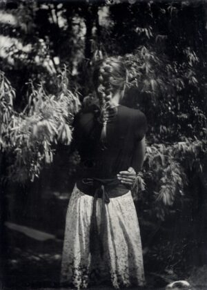 A woman standing in front of trees holding something.