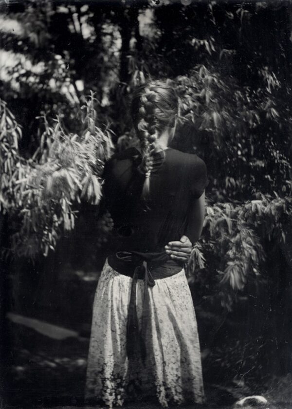 A woman standing in front of trees holding something.