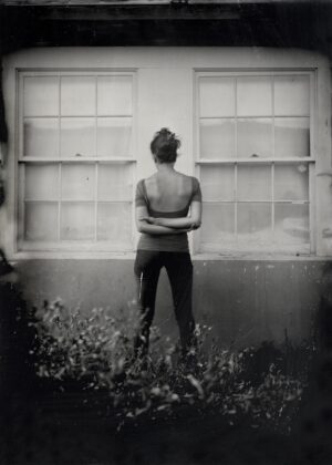A woman standing in front of two windows.