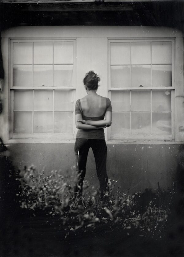 A woman standing in front of two windows.