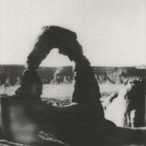 A black and white photo of a person sitting in front of a waterfall.