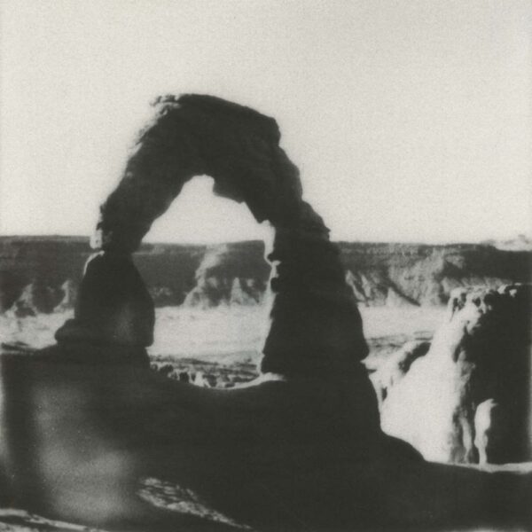 A black and white photo of a person sitting in front of a waterfall.