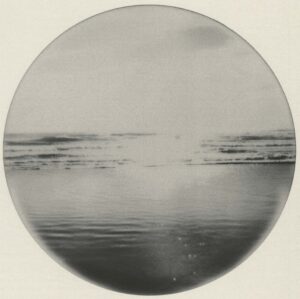 A circular photo of the ocean with waves coming in.