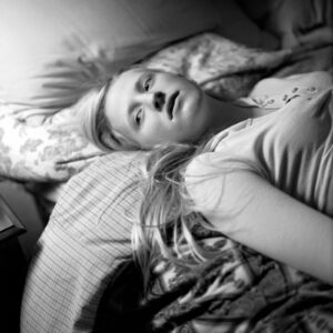 A woman laying in bed with pillows on her side.