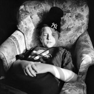 A person sleeping in an arm chair with a yankees hat on.