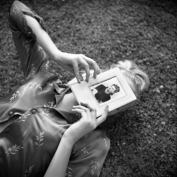 A woman laying on the ground holding an open book.