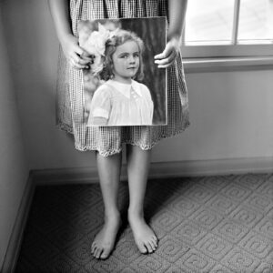 A woman holding a mirror with a picture of a girl.