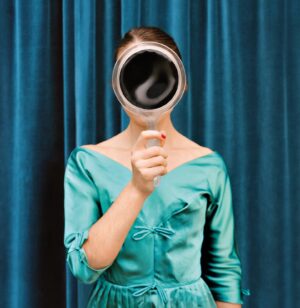 A woman in blue dress holding up a mirror.
