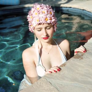 A woman in white bathing suit and pink hat.
