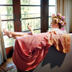 A woman laying on the couch in front of a window.
