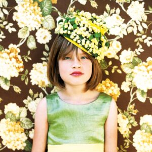 A young girl wearing a green dress and yellow hat.