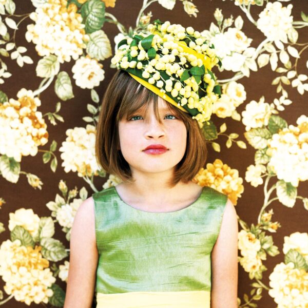 A young girl wearing a green dress and yellow hat.