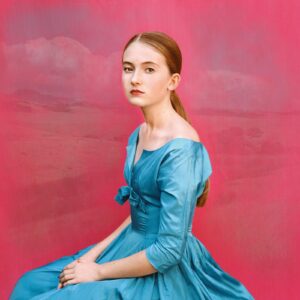 A woman in blue dress sitting on the ground.