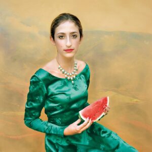 A woman in green dress holding watermelon.