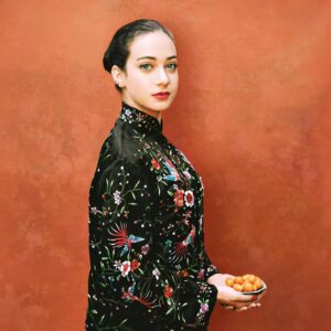 A woman in black and red dress holding food.