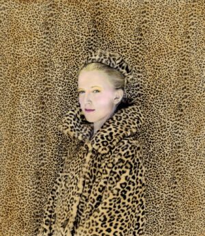 A woman in leopard print coat standing on fur.