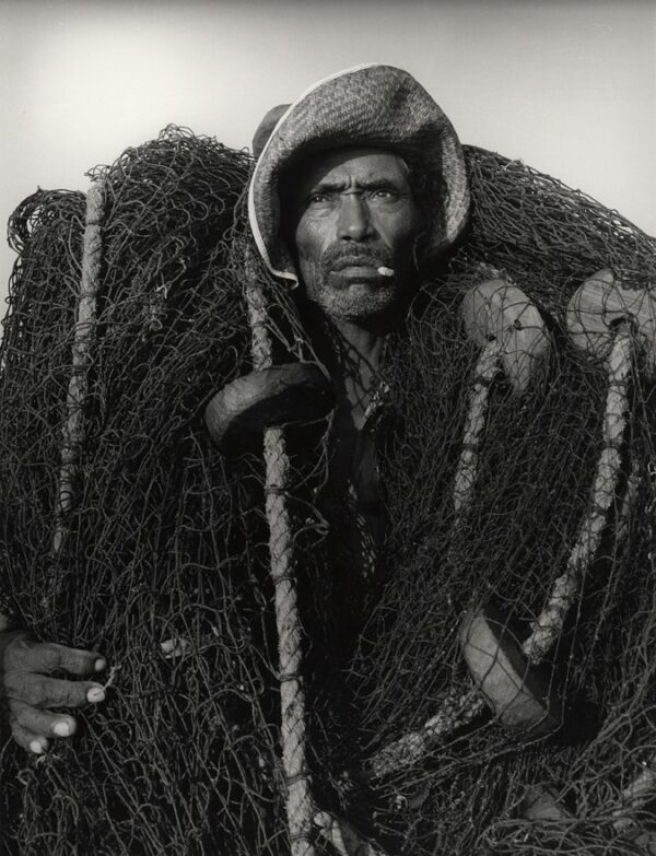 A man in a fur hat and coat holding two poles.