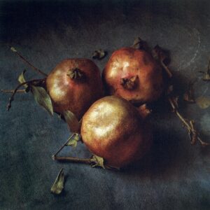 Three pomegranates on a table with leaves.