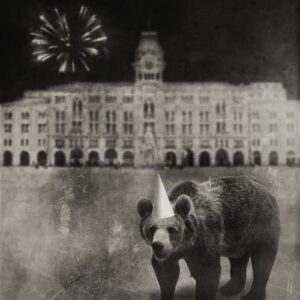 A bear with a party hat on in front of a building.