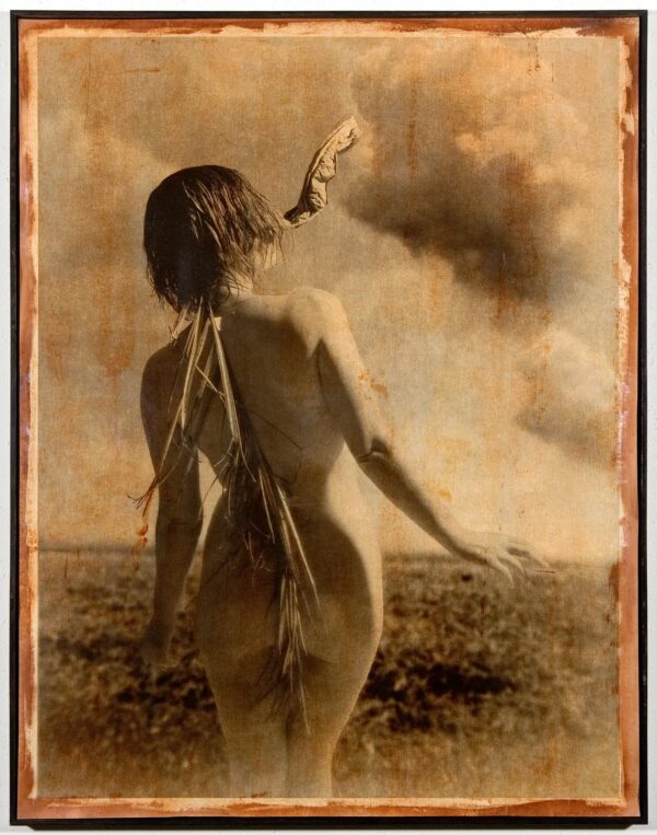 A woman standing in the grass with her back turned.