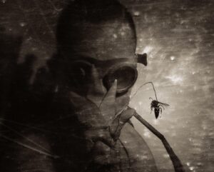 A man with a skull face and spider in the background.