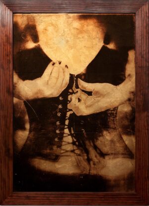 A woman in black shirt holding up a corset.