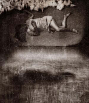 A black and white photo of a person laying on their stomach.