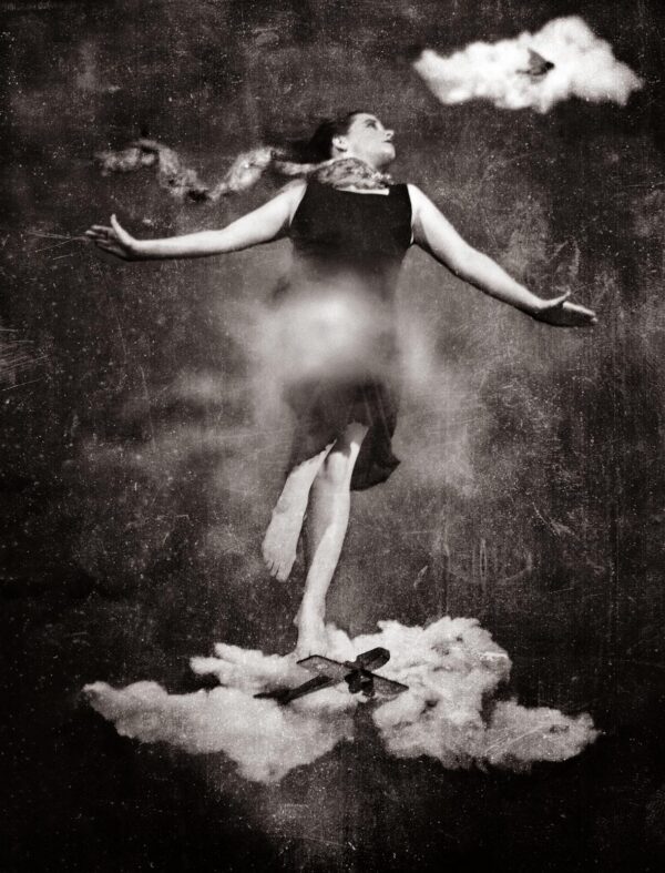 A woman standing on top of clouds with her arms outstretched.