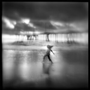 A person walking on the beach with an umbrella