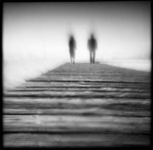 Two people standing on a pier in the water.