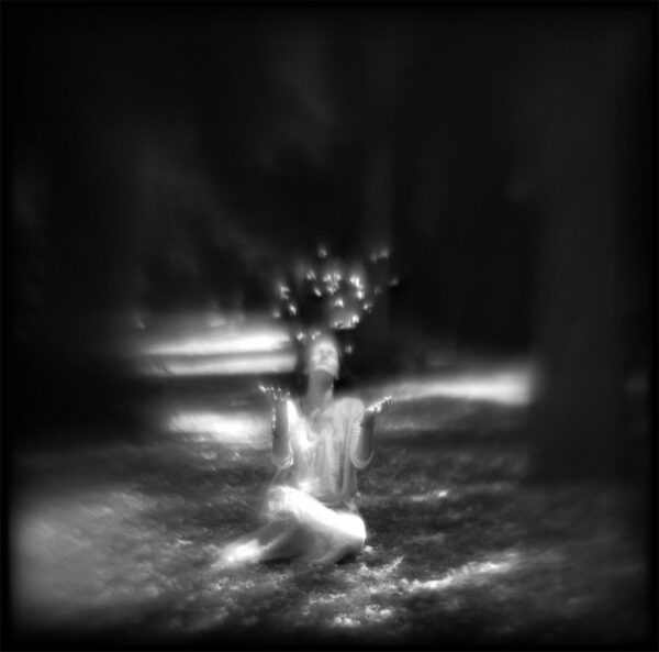 A blurry image of a woman sitting in the grass.