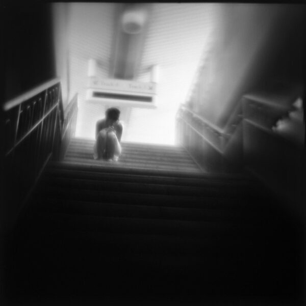 A person sitting on the stairs of an indoor building.