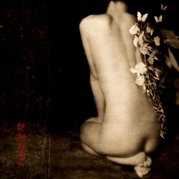 A nude woman sitting on the ground with flowers.