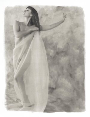 A woman wrapped in a towel standing on top of a beach.