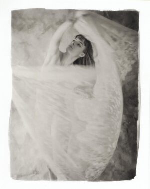 A woman in white dress holding onto the curtain