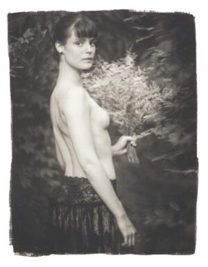 A woman with no shirt is holding something in her hand.