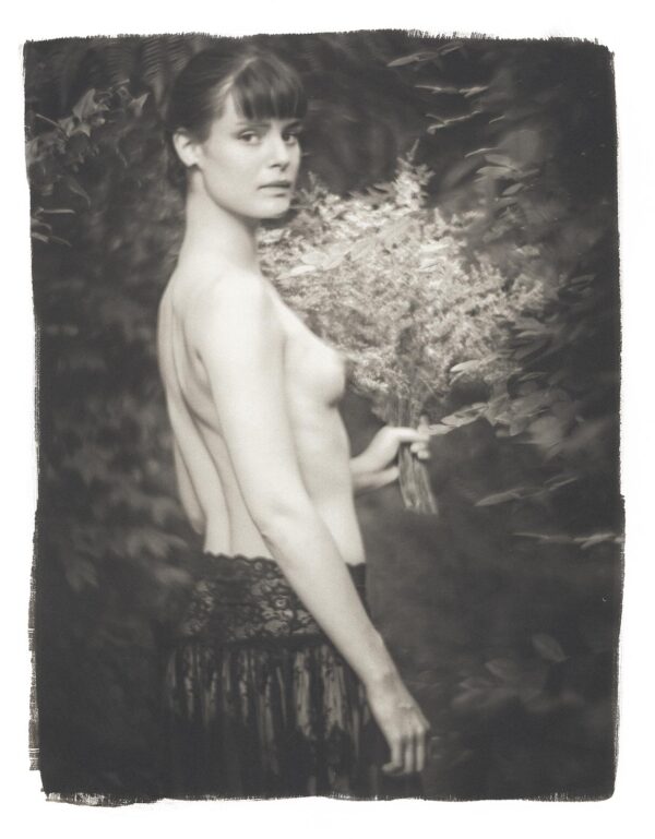 A woman with no shirt is holding something in her hand.