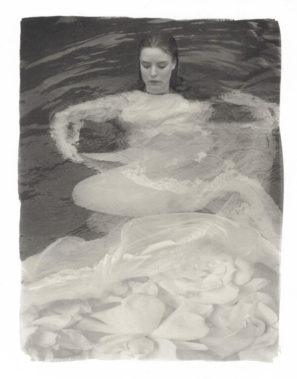 A woman in the water with her arms outstretched.