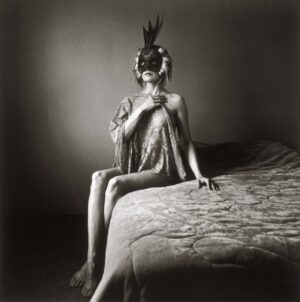 A woman sitting on top of a bed wearing a mask.