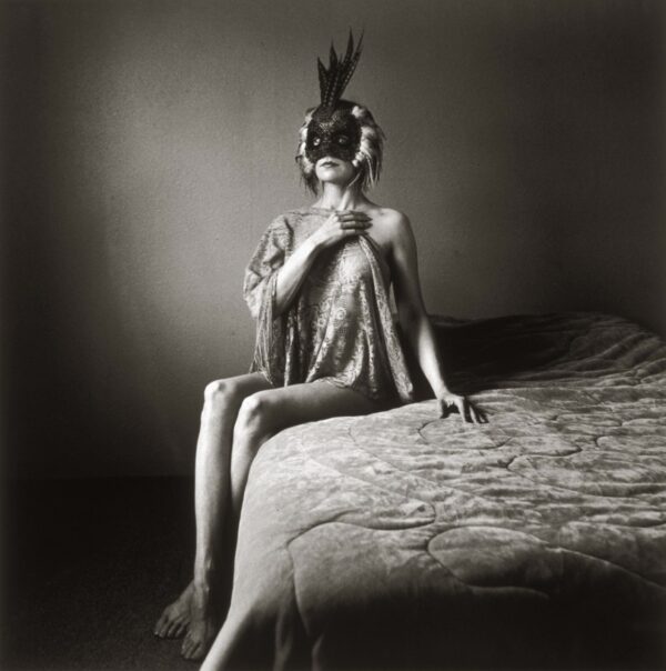A woman sitting on top of a bed wearing a mask.