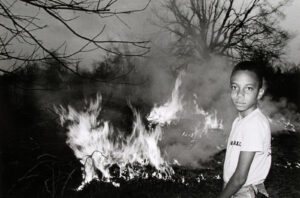 A young boy standing in front of fire.