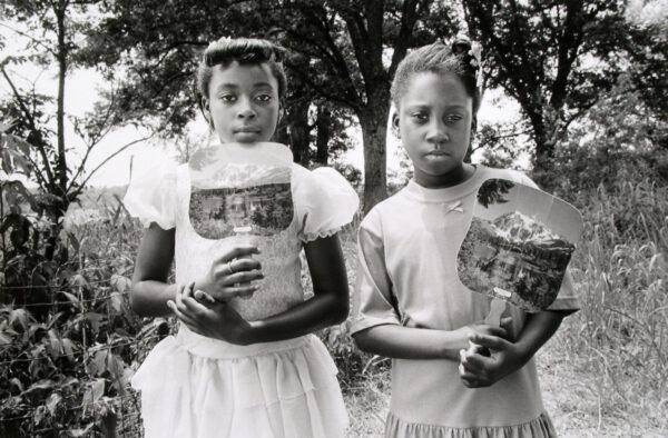 Two young girls holding baskets in a park.