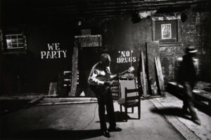 A man playing guitar in an empty room.