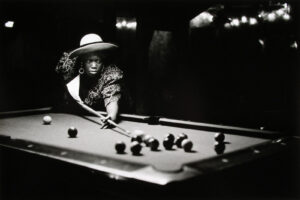 A woman in a hat playing pool on the table