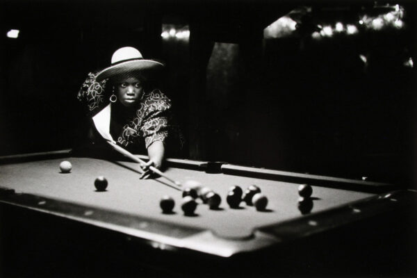 A woman in a hat playing pool on the table