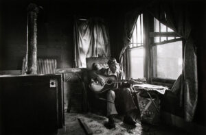 A man sitting on top of a couch holding a guitar.