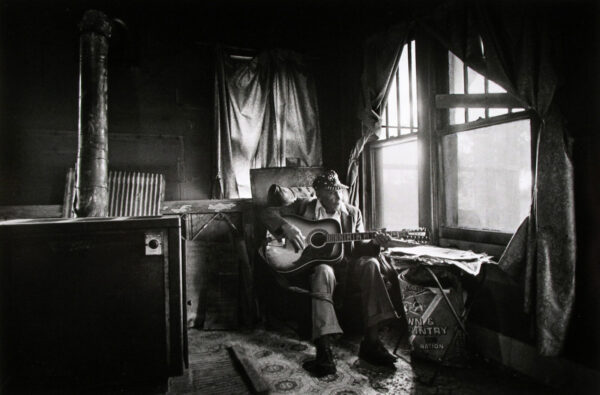 A man sitting on top of a couch holding a guitar.
